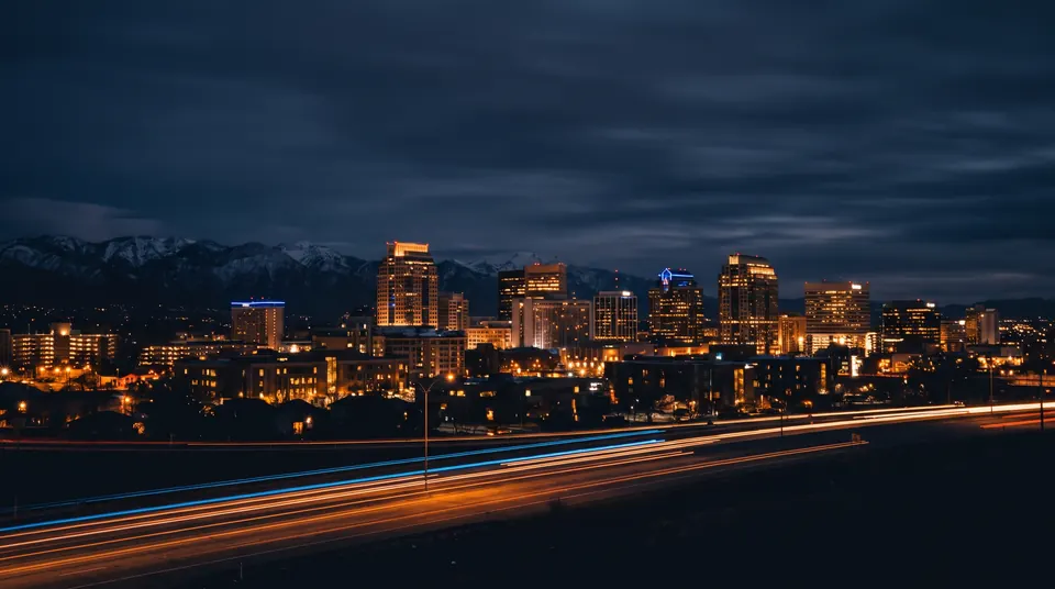 Downtown Salt Lake City skyline at night with warm window lights and the mountains behind