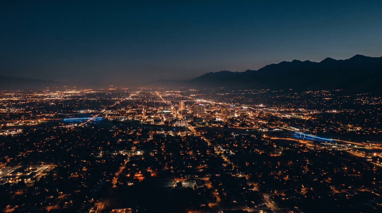 Aerial view of the Salt Lake City valley at blue hour with thousands of lights and the Wasatch mountains behind