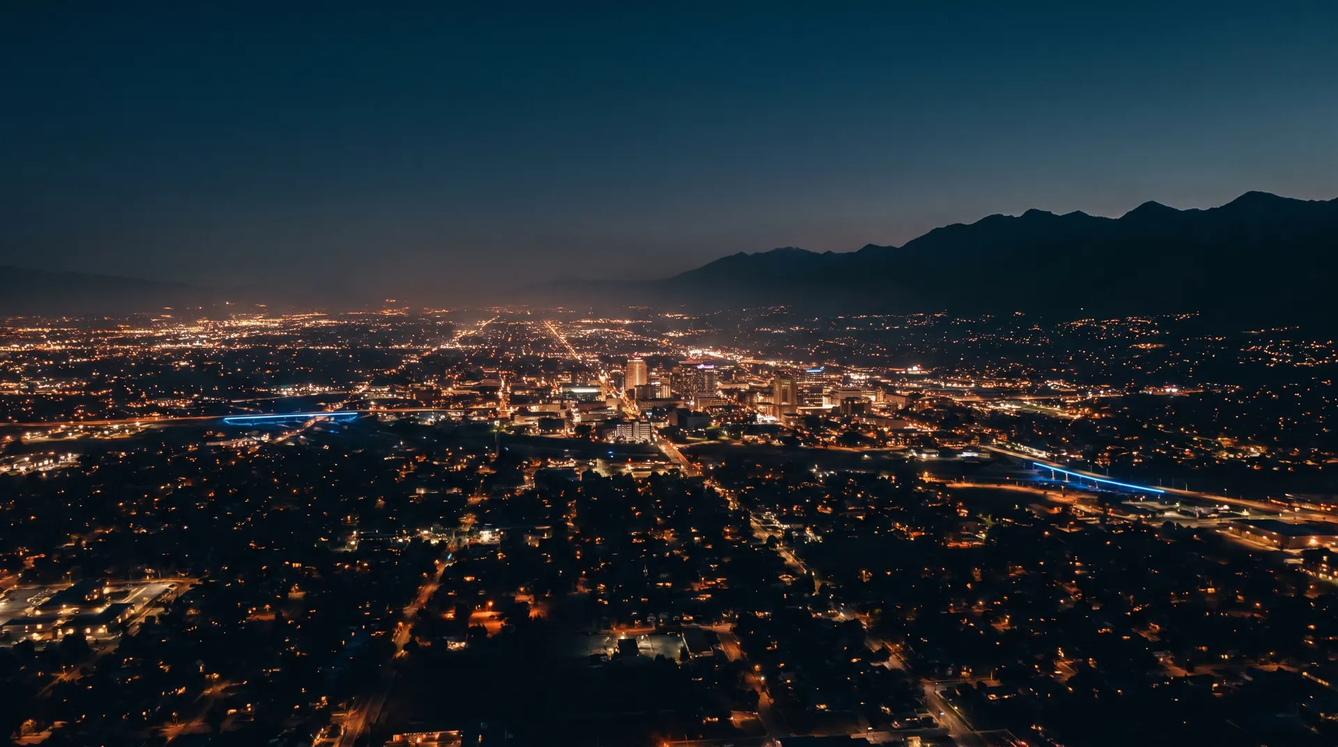 Aerial view of the Salt Lake City valley at blue hour with thousands of lights and the Wasatch mountains behind